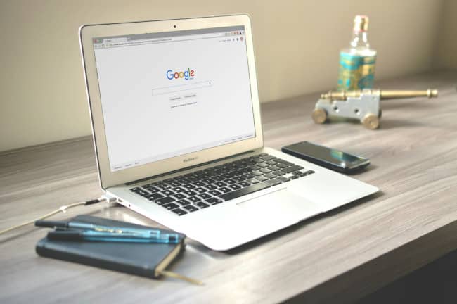 Macbook resting on a desk with the Google Search