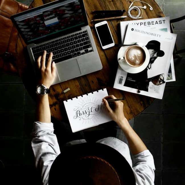 Top down view of someone coding and drawing on a desktop.